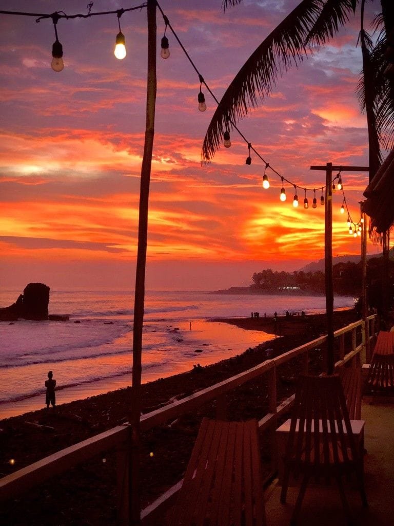 Atardecer en playa El Tunco visto desde una terraza con luces
