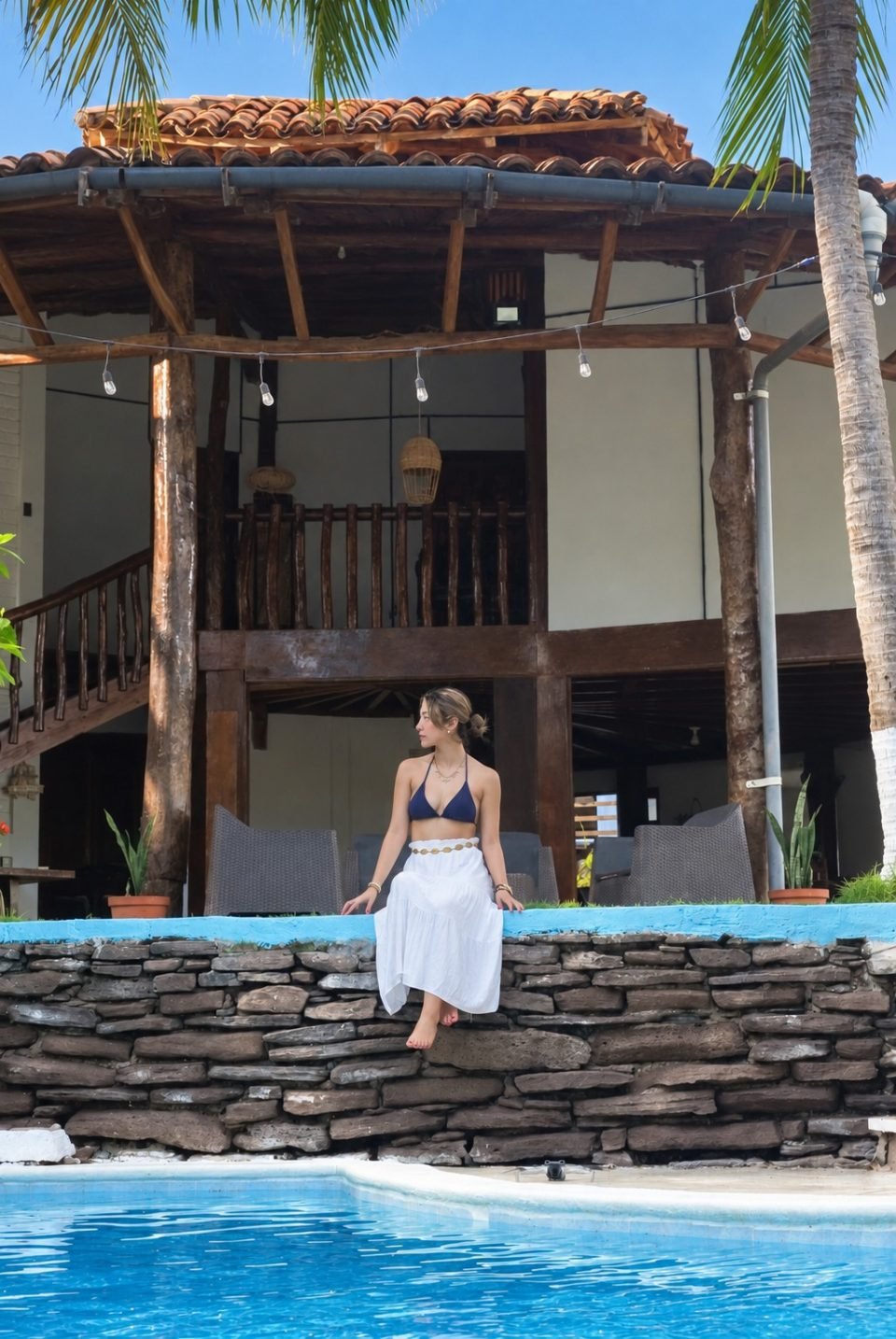Una huésped junto a la piscina y la villa tropical