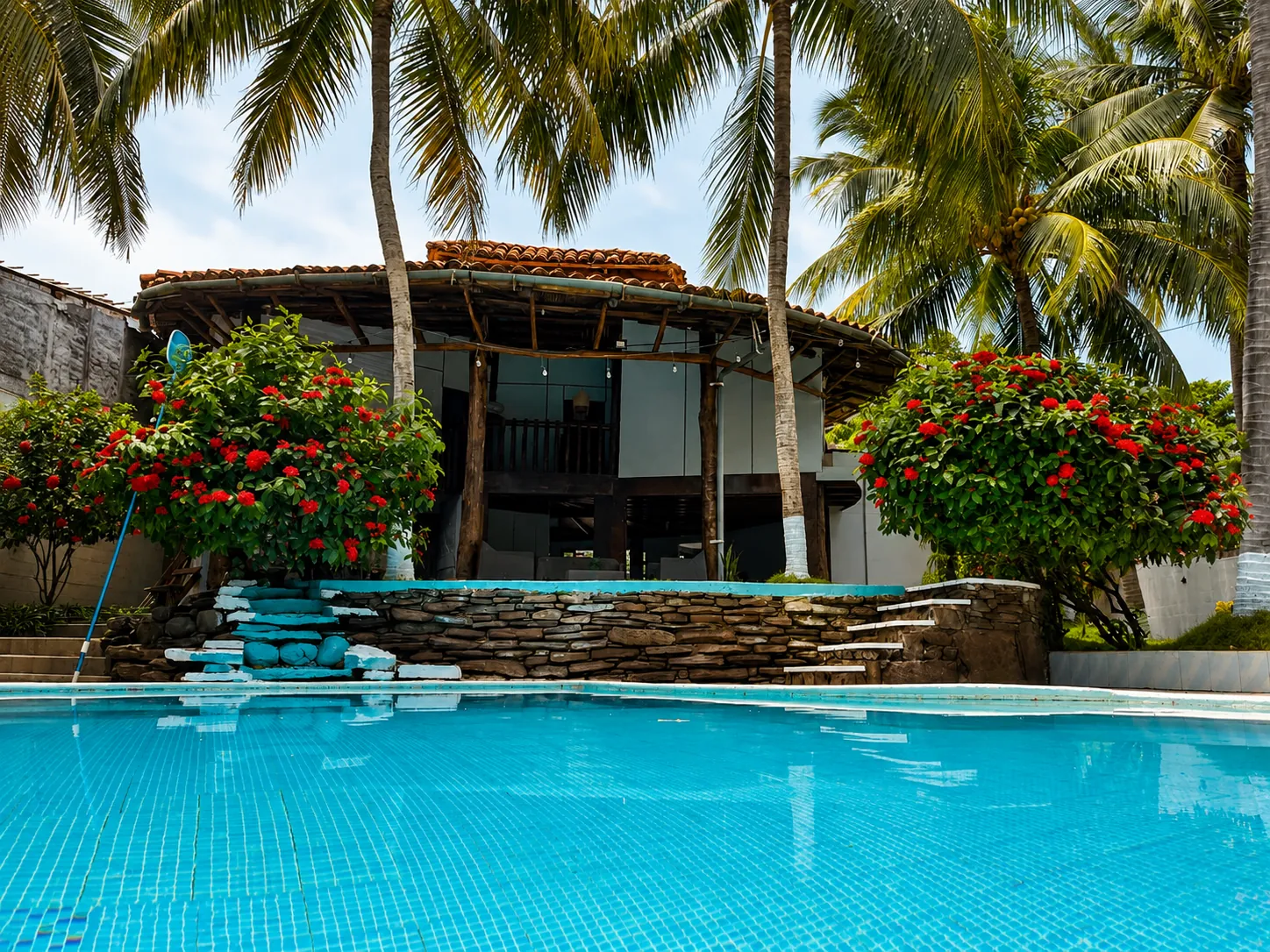 Piscina del hotel rodeada de palmeras y flores